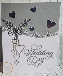 Polish_20260421_193038969 Handmade wedding day card with intricate silver cascading hearts, intertwined rings, botanical sprigs and ornate lace border on a pearl silver and white background.