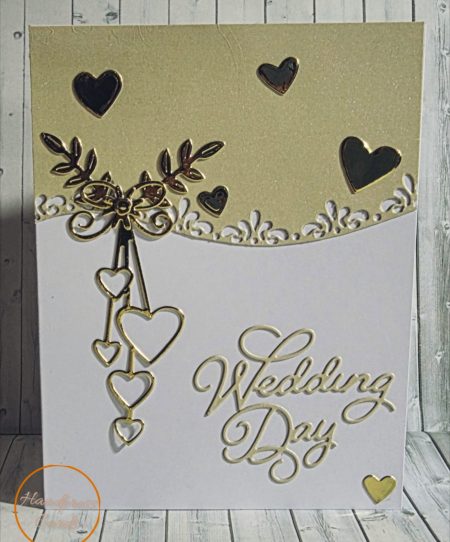 Handmade wedding day card with intricate gold cascading hearts, intertwined rings, botanical sprigs and ornate lace border on a pearl gold and white background.