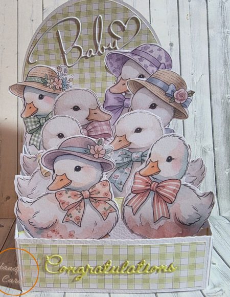 Handmade easel box card overflowing with layered die-cut watercolour ducklings in hats and bows, with a sage gingham box base, Baby heart arch topper and gold Congratulations sentiment — Handpress Cards