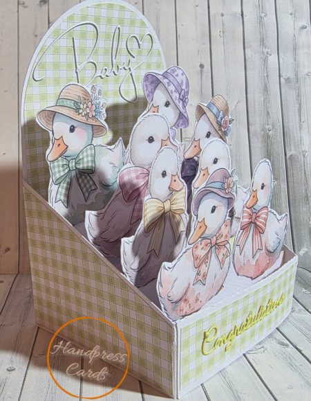Side angle of handmade baby duck easel box card showing depth of layered ducklings in coordinating hats and bows inside a sage gingham box — Handpress Cards