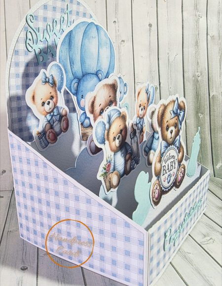 Side view of handmade easel box card showing layered three-dimensional die-cut teddy bears in blue and cream tones on a soft blue gingham background.