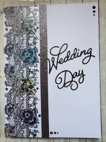 Handmade black wedding day card featuring intricate black lace panel with iridescent holographic teal and violet floral accents, vertical black glitter band, bold Wedding Day glitter die cut script sentiment and black gem embellishments