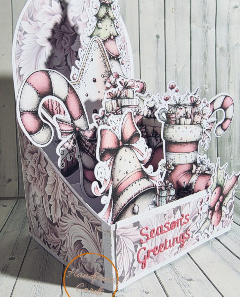 Handmade blush pink 3D box Christmas card with candy cane, bell, stocking and gifts, reading "Season's Greetings"