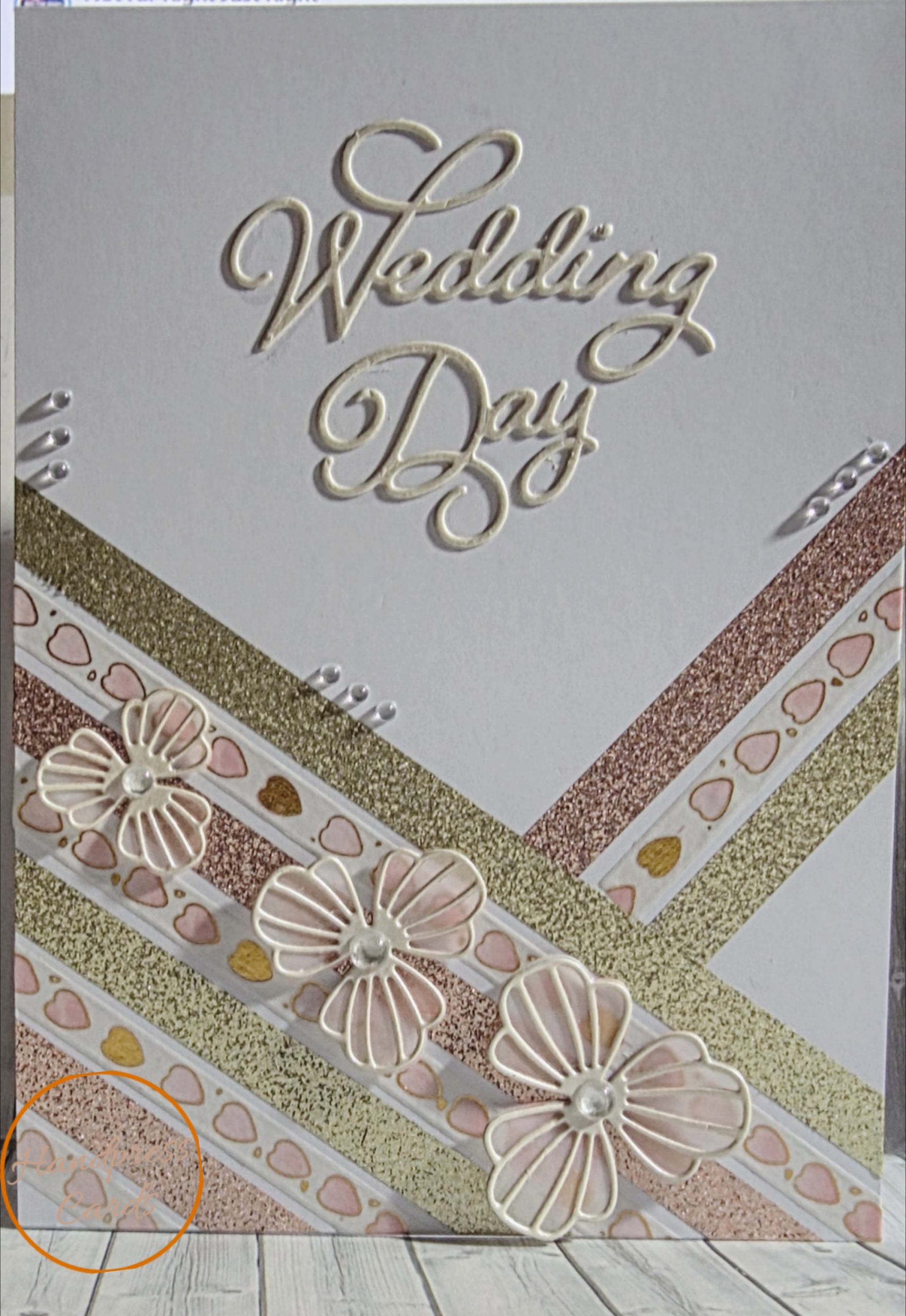 Handmade Wedding Day card with embossed cream lettering, rose gold and champagne diagonal trim, dimensional die-cut flowers and crystal embellishments on white background