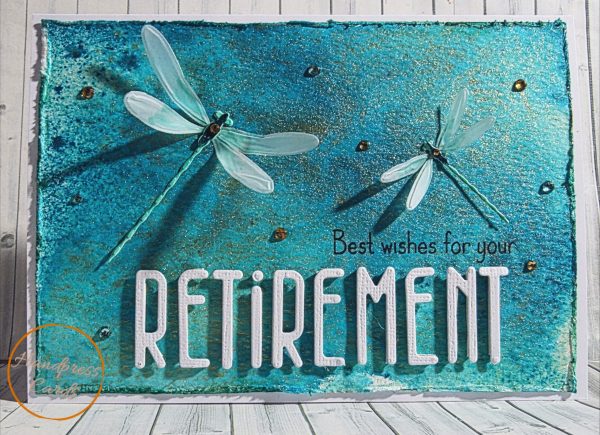 Handmade retirement card featuring two layered decoupage dragonflies on a textured teal and gold inked background with rhinestone gem accents and white die-cut RETIREMENT lettering, made in Victoria Australia by Handpress Cards