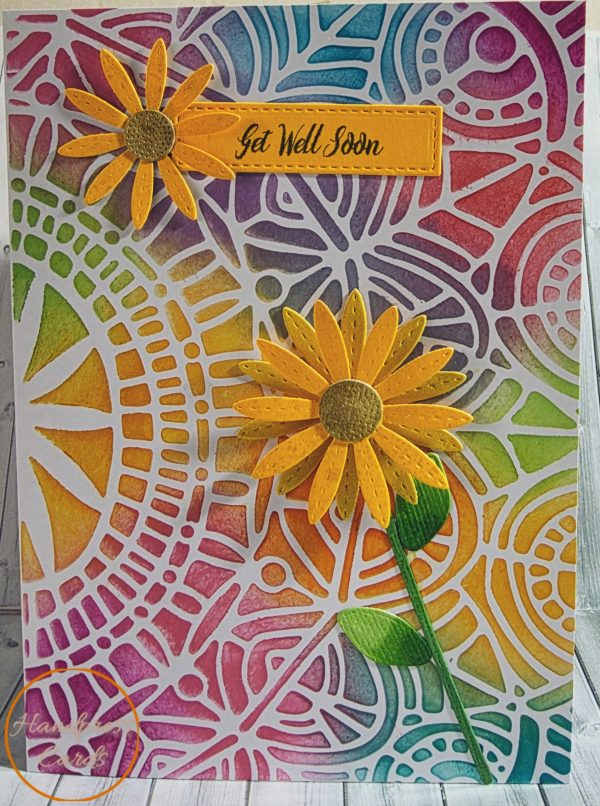 Handmade get well soon card featuring two layered decoupage sunflowers on a vibrant rainbow stencilled background with a green stem and bud, the larger sunflower has a spinning mechanism, made in Victoria Australia by Handpress Cards