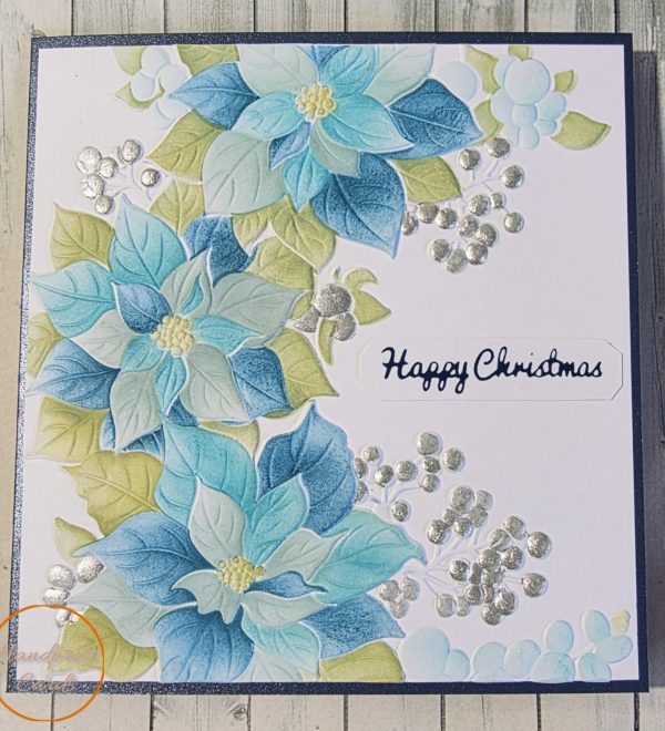 Handmade Christmas card with blue and green poinsettias, silver foiled berries and a Happy Christmas tag sentiment, by Handpress Cards